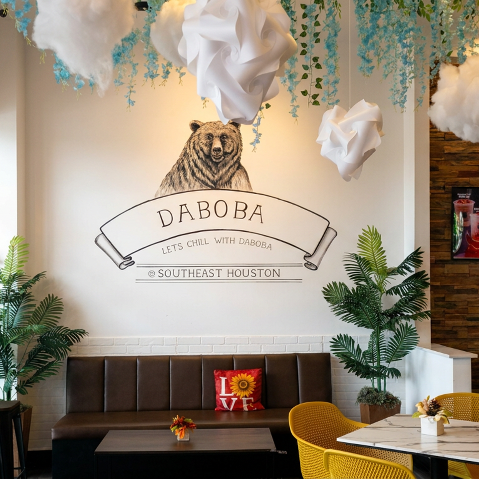 DABOBA Southeast Houston café interior with bear mural, hanging greenery, cloud decorations, plants, seating, and menu boards.