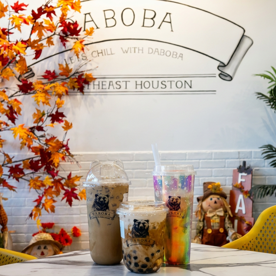 Cozy Daboba bubble tea shop interior with autumn decorations, branded drinks, yellow chairs, and a wall mural.