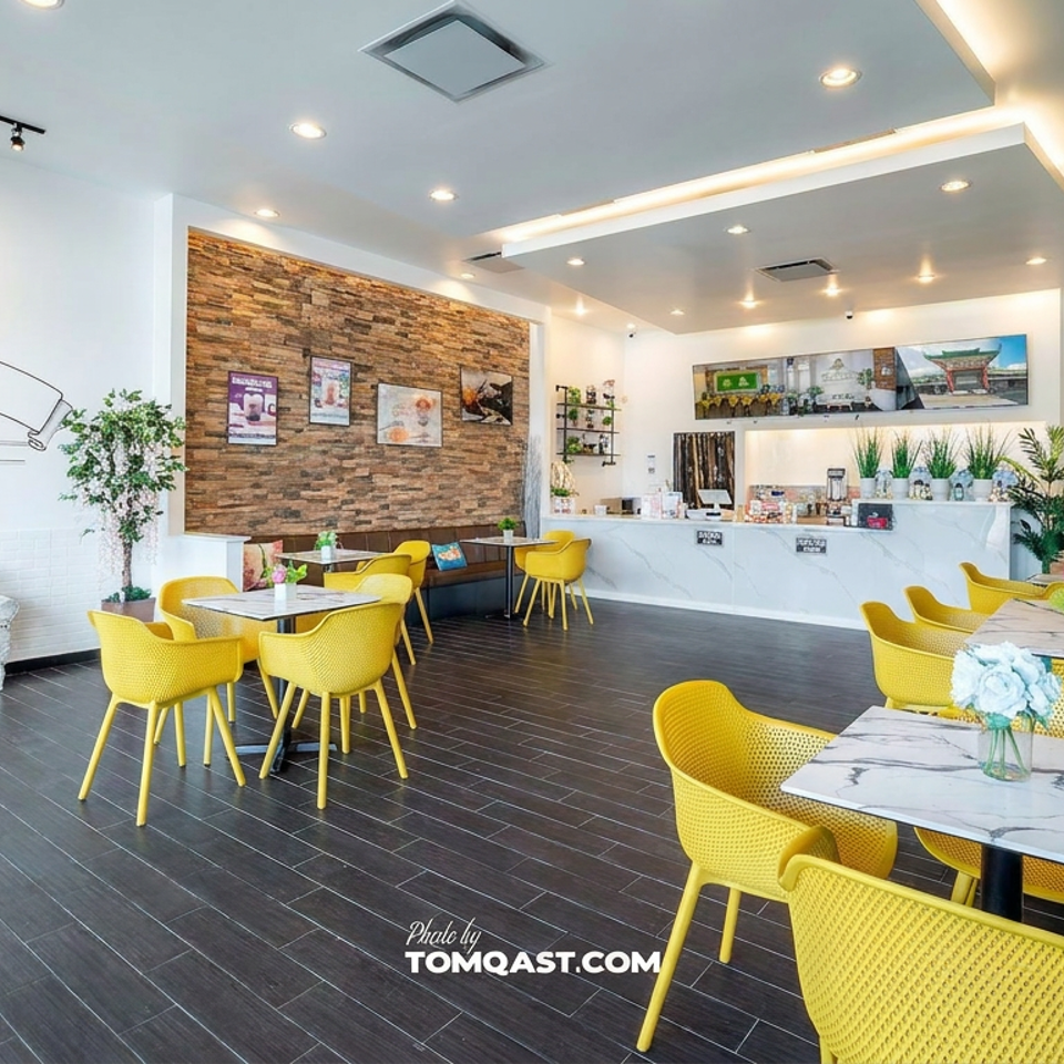 Bright Daboba bubble tea café interior with yellow chairs, marble tables, counter, greenery, and Southeast Houston branding.